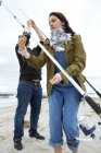 Young couple preparing sea fishing rods on beach — Stock Photo