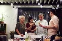 Gruppe von Menschen steht am Esstisch und hält Weingläser in der Hand — Stockfoto