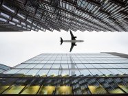 Low angle view of airplane flying  between modern buildings, London City Airport, London, UK — Stock Photo