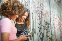 Deux jeunes femmes dans la rue, regardant smartphone — Photo de stock