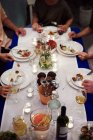 Grupo de pessoas sentadas à mesa, desfrutando de refeição, seção baixa — Fotografia de Stock