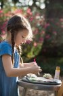 Вид сбоку на девочку, готовящую палитру красок в саду — стоковое фото
