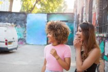 Две молодые женщины на улице, отводящие взгляд, смеющиеся — стоковое фото