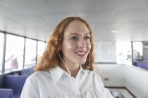 Mujer de negocios sonriente en auriculares en ferry de pasajeros - foto de stock