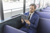 Молодий бізнесмен дивиться на цифровий планшет на пасажирському поромі — стокове фото
