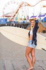 Portrait of young female surfer by amusement park on  beach, Santa Monica, California, USA — Stock Photo