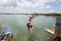 Homem maduro mergulhando na água da costa — Fotografia de Stock