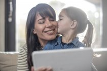 Woman and daughter on sofa using digital tablet — Stock Photo