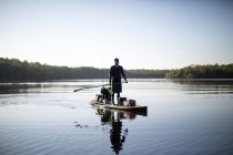 Hombre paddle boarding en aguas tranquilas - foto de stock