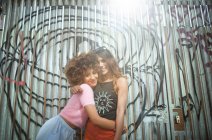 Porträt zweier junger Frauen, die sich in urbaner Umgebung umarmen — Stockfoto