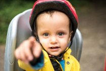 Porträt eines kleinen Jungen auf dem Kindersitz eines Erwachsenen-Fahrrades und zeigt — Stockfoto