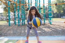 Молода дівчина підстрибує в баскетбол на дитячому майданчику — стокове фото