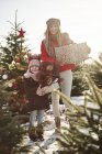 Chica y madre en el bosque de árboles de Navidad con regalos de Navidad, retrato - foto de stock