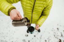 Hombre excursionista vertiendo café de frasco en taza - foto de stock