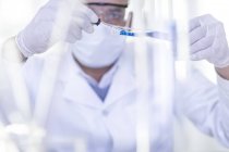 Laborangestellte mit Pipette Flüssigkeit aus Reagenzglas entnehmen — Stockfoto
