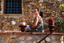 Зрелая женщина, выглядывающая со стены патио, Бегур, Каталония, Испания — стоковое фото