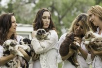 Young women and mature woman holding sheepdog puppies on ranch, Bridger, Montana, USA — Stock Photo