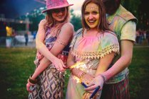 Portrait of two young women and covered in coloured chalk powder at festival — Stock Photo