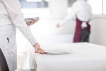 Waitress laying table in restaurant, mid section — Stock Photo