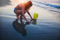 Girl drawing heart in sand on beach — Stock Photo
