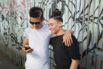 Двое молодых людей на улице, смотрят на смартфон — стоковое фото
