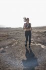 Junge Frau läuft in trockener Küstenlandschaft — Stockfoto