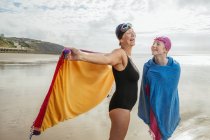 Mother and daughter standing on beach with shawls — Stock Photo