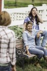 Tres mujeres jóvenes sonriendo en conversación al aire libre - foto de stock