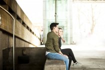 Jeune couple se détendre sur le banc sous le pont — Photo de stock