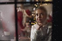 Junges Mädchen schaut aus dem Fenster, während der Weihnachtsmann Geschenke neben dem Baum hinterlässt — Stockfoto