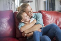 Мати і дочка на дивані, що обнімається і посміхається — стокове фото