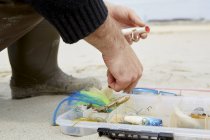 Colpo ritagliato di mano maschile preparazione amo da pesca sulla spiaggia — Foto stock