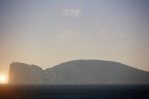 Vista costeira nebulosa com farol no topo do penhasco, Capo Caccia, Sardenha, Itália — Fotografia de Stock