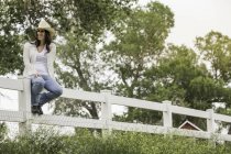 Young woman in cowboy hat sitting on ranch fence, Bridger, Montana, USA — Stock Photo