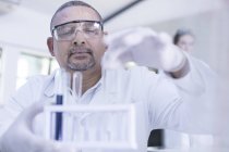 Labormitarbeiter holt Reagenzglas aus Regal — Stockfoto