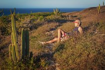 Man relaxing in grass, surrounded by cacti, Jericoacoara National Park, Ceara, Brazil — Stock Photo