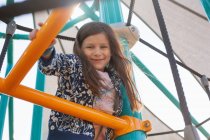Retrato de niña jugando en el patio de recreo y sonriendo a la cámara - foto de stock