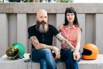 Tattooed hipster couple sitting on wall, portrait — Stock Photo