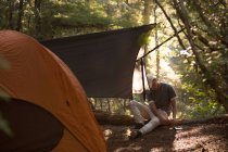Мальчик-подросток охраняет палатку к земле — стоковое фото