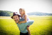 Retrato del hombre adulto medio dando a su hija un cerdito en el campo rural - foto de stock