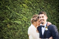 Portrait of bride and bridegroom with hedge at background — Stock Photo