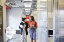 Zwei Geschäftsfrauen gehen den Büroflur entlang — Stockfoto