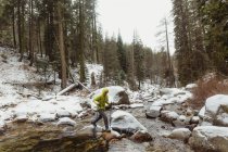 Чоловічий мандрівного, переступаючи через річку порід у snowy Національний парк Секвойя, Каліфорнія, США — стокове фото