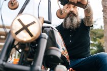 Low angle view of mature male hipster astride motorcycle — Stock Photo