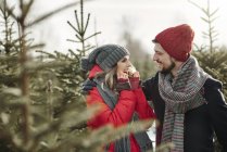 Joyeux jeune couple dans la forêt d'arbres de Noël — Photo de stock