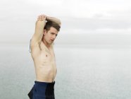 Hombre de pecho desnudo estirando brazos, Melbourne, Victoria, Australia, Oceanía - foto de stock