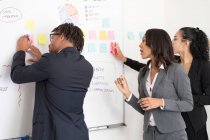 Empresário e empresárias, no cargo, brainstorming, vara ideias para quadro branco — Fotografia de Stock