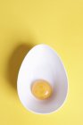 Vista aérea de la yema de huevo en cuenco ovalado sobre fondo amarillo - foto de stock