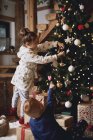 Mädchen und Junge schmücken Weihnachtsbaum — Stockfoto
