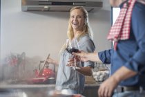 Homme et femme dans la cuisine préparant la nourriture avec un verre de vin — Photo de stock